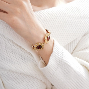 Detail of vintage gold bracelet with red oval gemstones and small diamonds on model