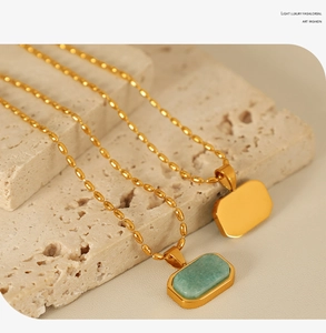 Macro shot of gold plated rectangle pendant with green textured stone on a bead chain