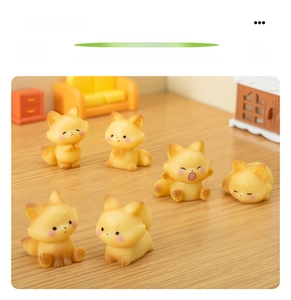 Detail of 6 mini resin foxes in different poses like stretching and sleeping on a wooden table
