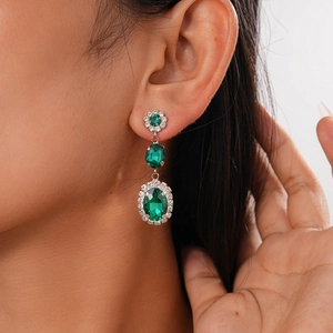 Close-up of three-tier emerald drop earrings with sparkling rhinestones on model