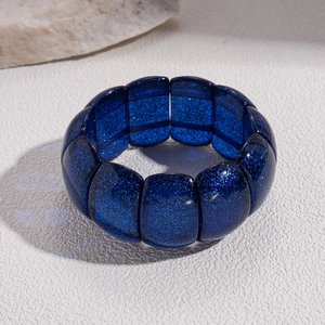 Macro detail of wide dark blue glitter acrylic bracelet with geometric resin tiles