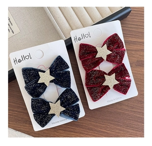 Detail of velvet bow hair clips with gold stars in dark blue and deep red colors