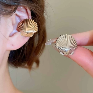 Detailed macro of gold and silver shell ear clips showing fine radial metal textures