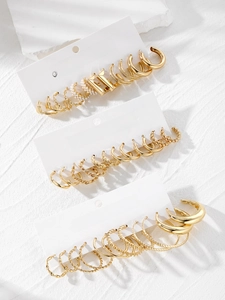 Detail of 16-piece gold earring set featuring pearls and hoops on marble display