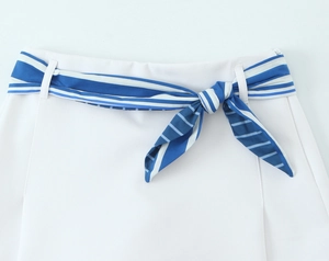 Detail of white trousers with blue striped silk scarf belt and bow knot tied at the waist