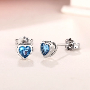 Macro shot of silver heart stud earrings featuring vibrant blue heart-shaped gemstones