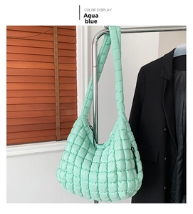 Detail of aqua blue quilted puffy cloud bag showing soft padded texture and strap