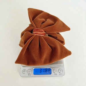 Detail view of a brown velvet bow hair clip on a digital scale showing 31.88g weight