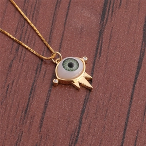 Detailed close-up of evil eye pendant with green enamel and sparkling crystals on gold chain