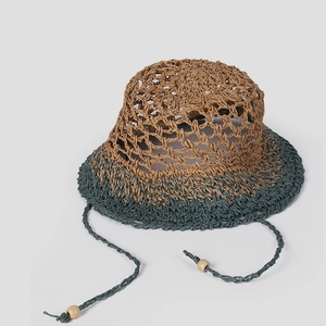 Detail of hollow-out hand-woven straw hat with two-tone green brim and adjustable ties