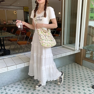 Detail of white hollow lace tiered skirt and cotton printed t-shirt with floral crossbody bag