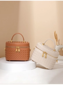 Detailansicht von geflochtenen Leder-Kosmetiktaschen in Braun und Beige mit goldener Hardware.