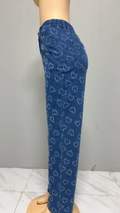 Detail of blue denim straight leg jeans featuring all-over heart patterns and elastic waistband