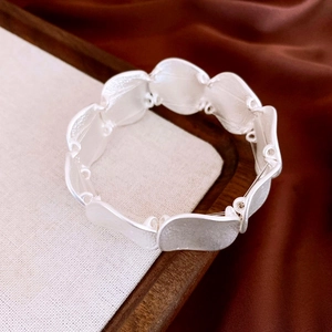 Detailed view of silver wavy textured geometric link bracelet on linen and satin background