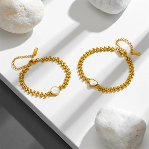 Gold stainless steel bracelets with heart and round sea shell charms on stone steps
