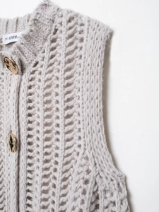 Dettaglio del gilet grigio chiaro a maglia grossa con trama traforata e bottoni d'oro