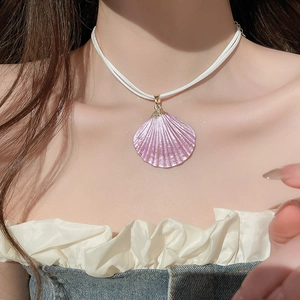Detail of purple seashell pendant necklace with dual white cords on a model neck