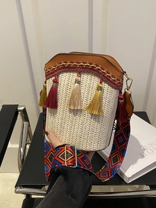 Detail of woven bucket bag featuring colorful tassels and ethnic embroidered strap