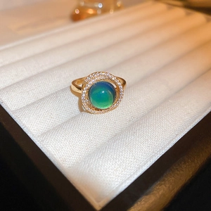 Close-up of gold-plated dragon ring with gradient green stone and zircon halo