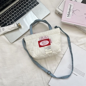 Vue détaillée du mini sac matelassé avec broderie cerise et anses en denim bleu