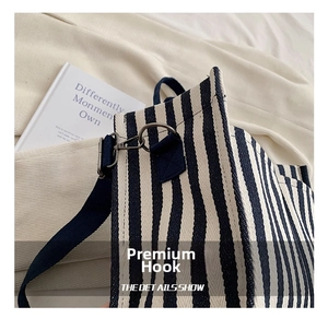 Detail of grey metal hook and shoulder strap connector on blue striped canvas tote bag