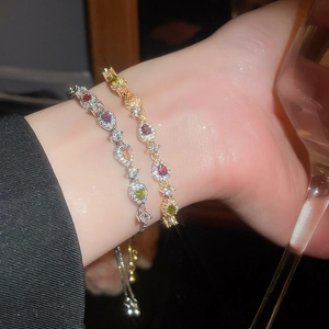 Detail of elegant gold and silver bracelets featuring colorful pear-cut gemstones