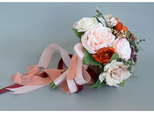 Detailed close-up of bridal bouquet with pink roses and elegant fraying ribbons