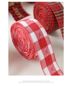 Macro shot of red plaid Christmas ribbon roll with textured burlap and Joy print detail
