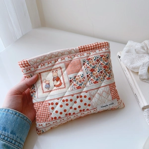 Gros plan d'une trousse à maquillage matelassée en coton aux motifs floraux et lapins