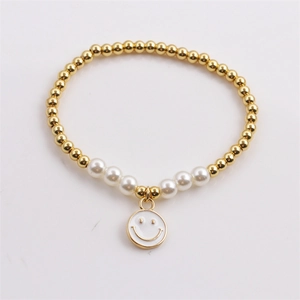 Gold-plated beaded bracelet with white pearls and smiling face pendant on white background