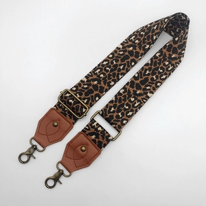 Close-up of leopard print canvas strap with brown leather ends and bronze metal buckles