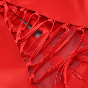 Detail of red dress showing criss-cross lace-up design with mesh and hidden zipper