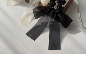Detailed texture of black organza bow hair clip with long ribbons and elegant shadows