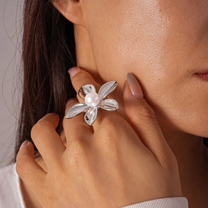 Close-up of a silver flower ring with a large white pearl worn on a finger