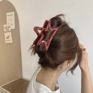 Elegant star-shaped hair claw in deep red resin shown on a woman's hair for daily styling