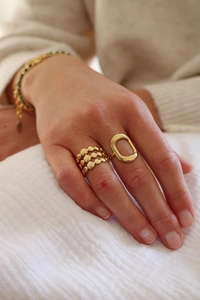 Close-up of gold geometric hollow and layered stainless steel rings on a hand