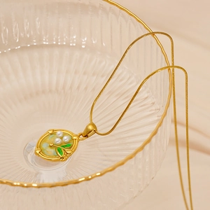 Macro detail of vintage floral pendant with pearls and green enamel on a snake chain