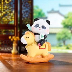 Detail of cute panda figurine riding a yellow rocking horse with lucky jade pendant