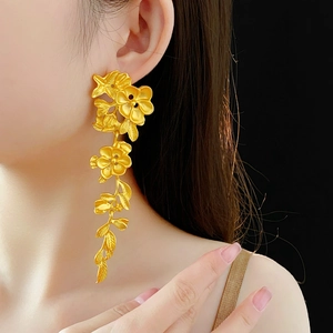 Gros plan de boucles d'oreilles pendantes fleurs dorées sur mannequin, lumière de qualité