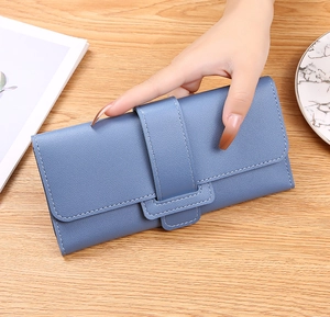 Detailed view of long blue leather wallet with crossgrain texture on wooden table