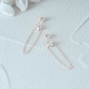 Detail of 925 sterling silver tassel earrings with round cubic zirconia on textured surface