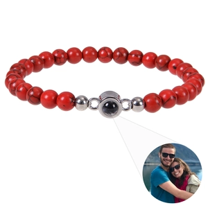 Gros plan des perles de 6mm en pierre rouge et du pendentif argenté avec projection photo