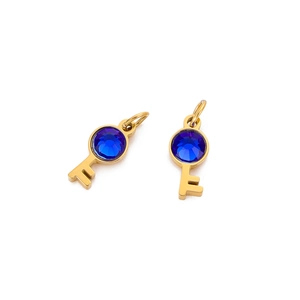 Detail of two golden key pendants with blue gemstones on a clean white background