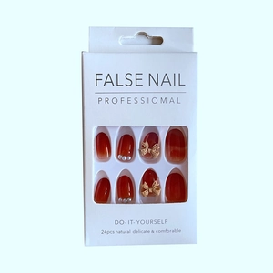 Detail of amber gradient press-on nails with 3D bows and pearl accents in packaging