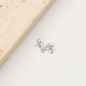 Macro view of a silver unicorn stainless steel pendant on a textured stone surface