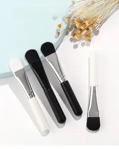 Detailed view of four facial mask brushes with soft bristles and silicone heads on a white base