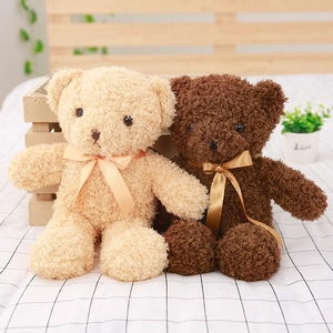 Plush teddy bear toy shells in beige and brown with ribbon bows on wooden background