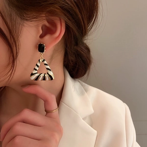 Detail of zebra pattern triangle earrings with gold finish and black rectangular gems