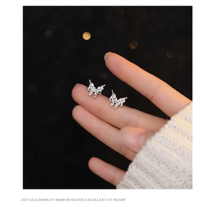 Macro detail of molten silver butterfly stud earrings with irregular mirror texture