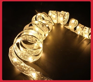 Macro view of warm white LED ribbon lights with silver star patterns on black background